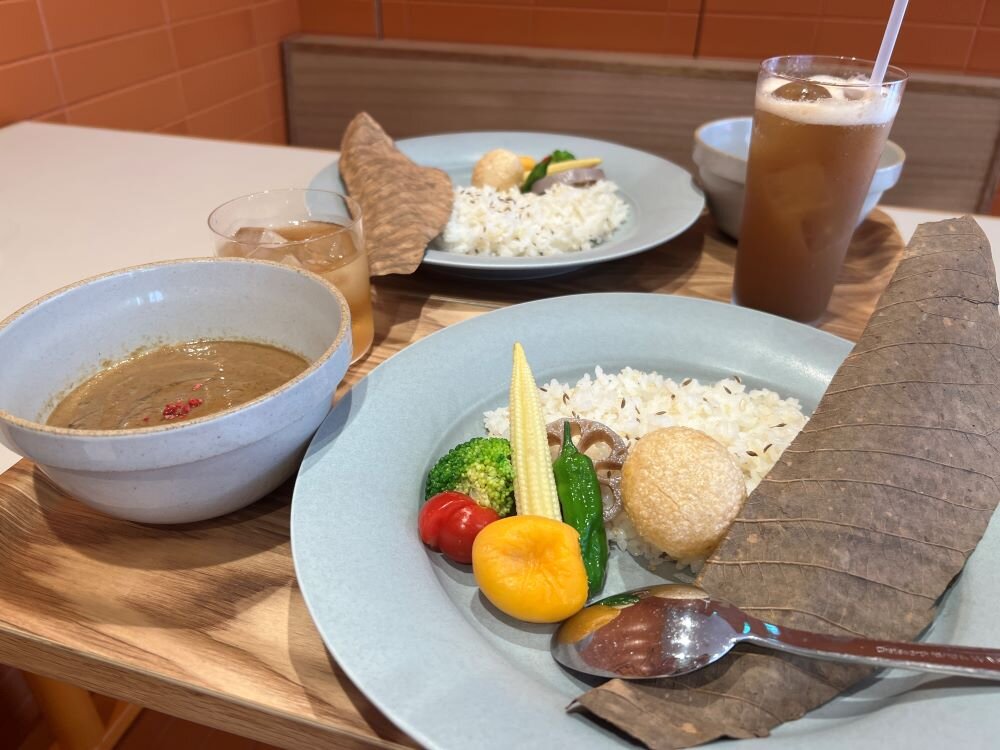 定番の「果実とスパイス香るカレー」と週替わりの「白トリュフ香るオーツミルクと茸のカレー」。ドリンクは「自家製クラフトコーラ」と「オリジナルハーブティーのクロモジ茶」