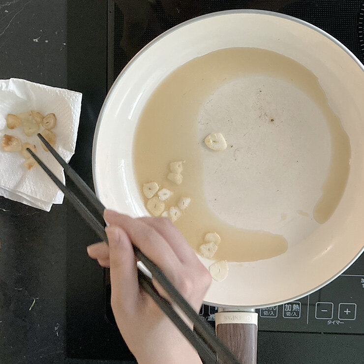 ニンニクチップを作ります。フライパンにゴマ油を入れてニンニクを入れます。 弱火でニンニクを揚げ焼きにします。