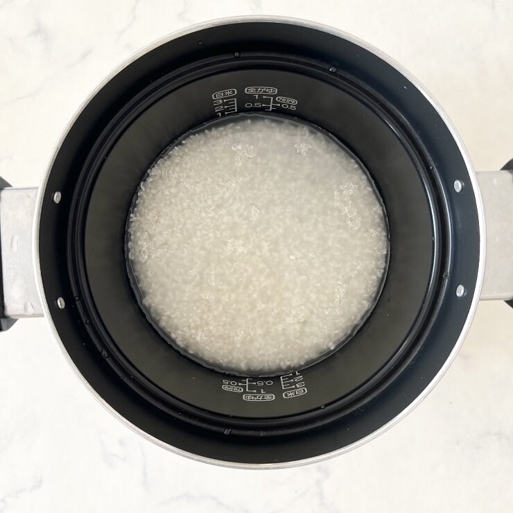 米は洗ってザルに上げ、分量の水に浸水させた後、酒を加えて炊きます。